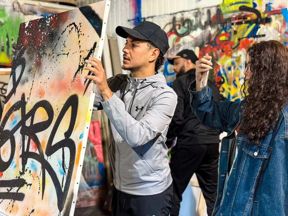 Un participant présente sa toile pendant qu'une collègue la photographie